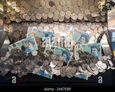 Money is seen in a 'coin pusher' arcade game in Swanage, Dorset, November 2019. Stock Photo