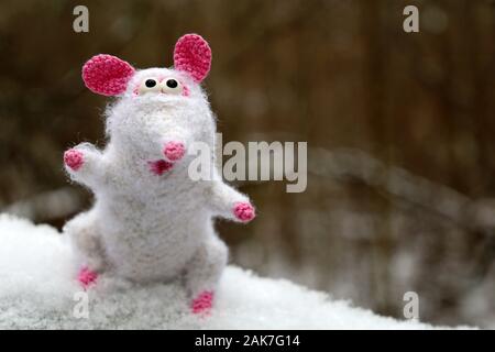 White knitted toy rat on the snow in winter forest, New Year card. Chinese Year of Rat, Zodiac symbol 2020 Stock Photo