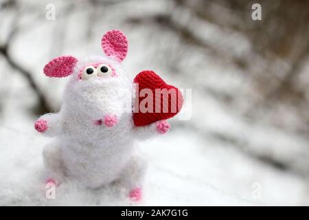 White knitted toy rat with red heart on the snow in winter park, New Year and Valentine card. Chinese Year of Rat, Zodiac symbol 2020 Stock Photo