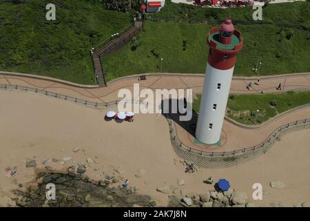 Durban, KwaZulu-Natal, South Africa, aerial view, landscape, lighthouse, people walking on promenade of Umhlanga Rocks waterfront, umbrellas on beach Stock Photo