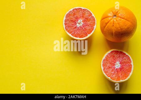 Top view whole and sliced ripe grapefruit and orange on a yellow surface, concept of health and vitamins Stock Photo