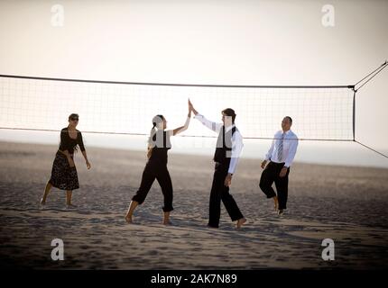 Two couples are playing volleyball on the beach. Stock Photo