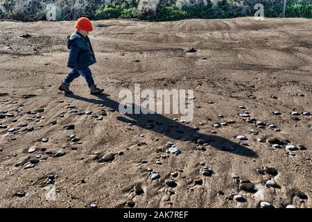 Three years old baby boy walking on a empty beach at winter time Stock Photo