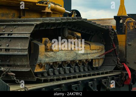 Close up detail of a continuous tread, aka caterpillar track, on a heavy plant machine. Tracked construction vehicle chained to a loader for transport Stock Photo