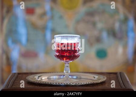 wine glass on silver platter on wooden table with ancient world map as background Stock Photo