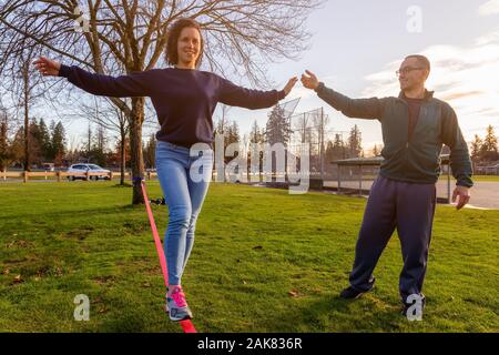 Couple walking on a Slackline in the Park Stock Photo