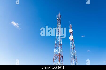Colorful mobile phone network telecommunication tower against blue sky. Stock Photo