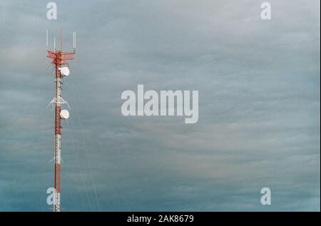 Colorful mobile phone network telecommunication tower against blue sky. Stock Photo