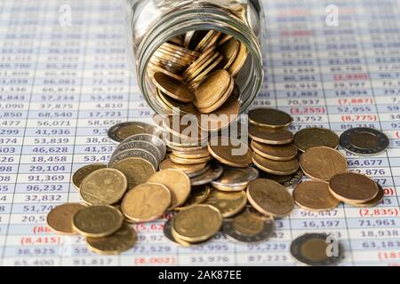 Couns spilling out of a jar on spreadsheet Stock Photo