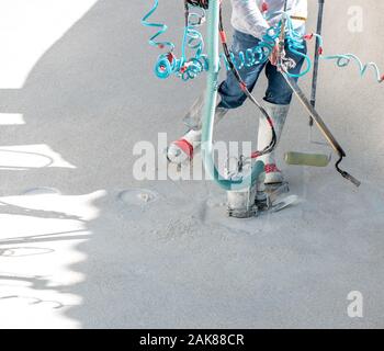 Man using a propane torch, roller, and sump pump during a swimming pool renovation Stock Photo