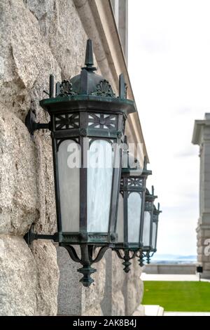 Close up of vintage style iron lanterns on the white stone wall of building Stock Photo