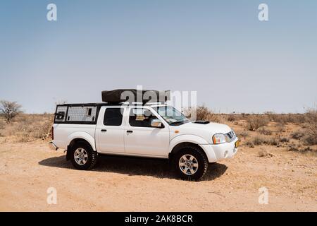 Tent located on the roof of a pickup 4x4 car on lonely desert street in Africa Stock Photo