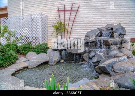 Artificial stone cascade waterfall in backyard on a sunny day Stock Photo