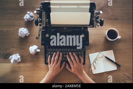 Top view of red vintage typewriter with white blank paper sheet with female hand typing Stock Photo