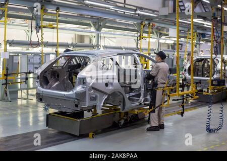 Russia, Izhevsk - December 14, 2019: LADA Automobile Plant Izhevsk. The workers put doors on the body of new car. Modern car manufacturing enterprise. Stock Photo