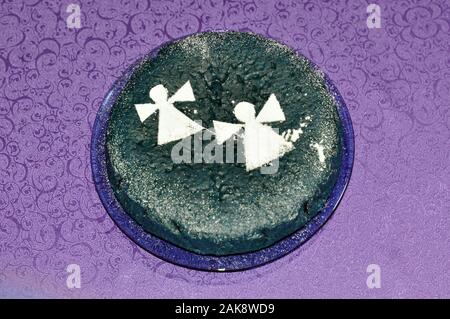 Festive cake decorated with silhouettes of angels on a lilac background. Christmas Stock Photo