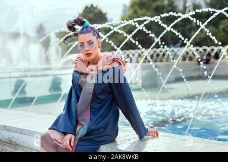 Young funky girl with trendy avant garde fashion style and crazy hair on city street Stock Photo