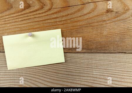 A pinned piece of paper hangs on a wooden wall. Stock Photo