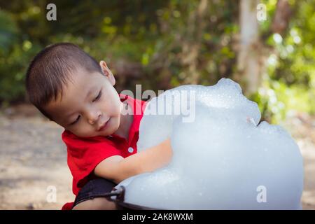 เด็กชายตัวเล็ก ๆ กำลังเล่นเป่าและเป่าฟองสบู่ในมือ Stock Photo