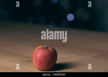 Red apple isolated on a wooden table on a dark blurry background Stock Photo