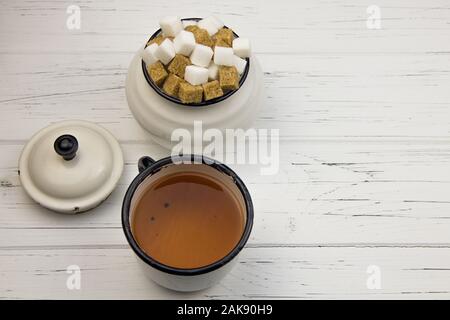 tea in an aluminum cup and sugar cubes in an aluminum sugar bowl on a light wooden background Stock Photo