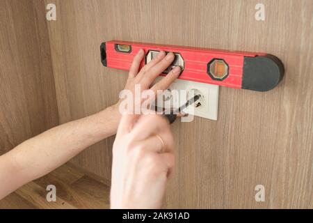 Hands of electrician worker installing electrical outlet in furniture Stock Photo