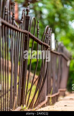 Close up of rusty and old iron fence on top of stone wall on a sunny day Stock Photo