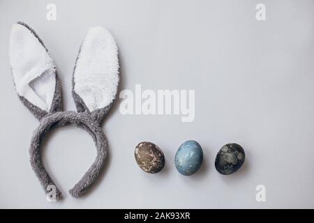 Stylish easter eggs and bunny ears flat lay on gray wallpaper with copy space. Natural dyed marble easter eggs and grey rabbit ears. Seasons greetings Stock Photo