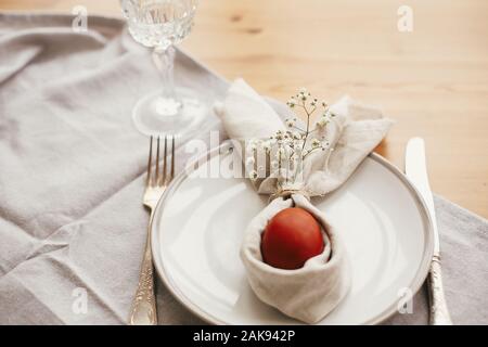Easter table decorations. Stylish Easter brunch table setting with egg in easter bunny napkin on  table. Natural dyed easter egg on napkin with bunny Stock Photo