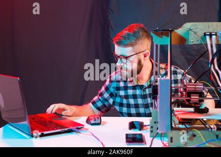 Young male designer engineer using a 3D printer in the laboratory and studying a product prototype, technology and innovation concept. Stock Photo