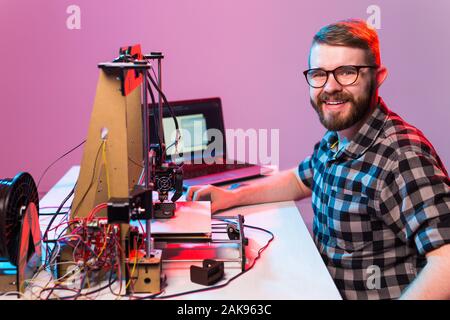 Young male designer engineer using a 3D printer in the laboratory and studying a product prototype, technology and innovation concept. Stock Photo