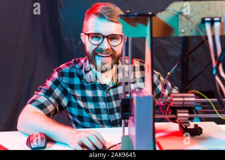 Technology and engineering concept - Male engineer working at night in the lab, he is adjusting a 3D printer components Stock Photo
