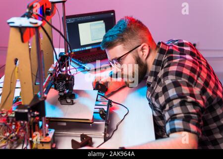 Young male designer engineer using a 3D printer in the laboratory and studying a product prototype, technology and innovation concept. Stock Photo