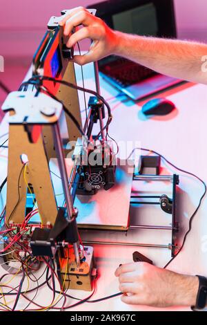Young male designer engineer using a 3D printer in the laboratory and studying a product prototype, technology and innovation concept. Stock Photo