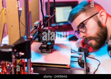 Young male designer engineer using a 3D printer in the laboratory and studying a product prototype, technology and innovation concept. Stock Photo