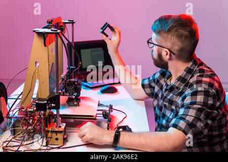 Young male designer engineer using a 3D printer in the laboratory and studying a product prototype, technology and innovation concept. Stock Photo