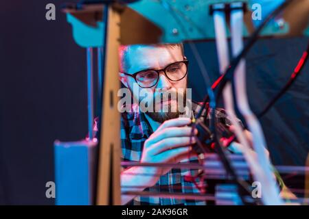Young male designer engineer using a 3D printer in the laboratory and studying a product prototype, technology and innovation concept. Stock Photo