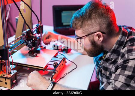 Young male designer engineer using a 3D printer in the laboratory and studying a product prototype, technology and innovation concept. Stock Photo