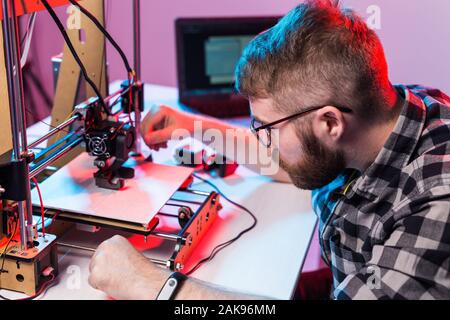 Young male designer engineer using a 3D printer in the laboratory and studying a product prototype, technology and innovation concept. Stock Photo