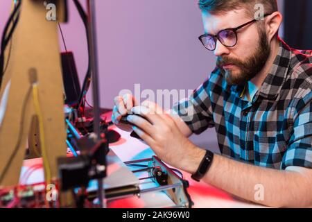 Young male designer engineer using a 3D printer in the laboratory and studying a product prototype, technology and innovation concept. Stock Photo