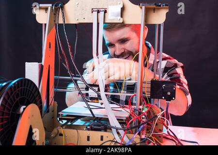 Young male designer engineer using a 3D printer in the laboratory and studying a product prototype, technology and innovation concept. Stock Photo
