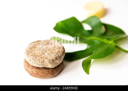 solid shampoo discs close up with green natural leaf, example of natural and ecological plastic free cosmetic, homemade with herbs Stock Photo