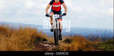 male cyclist athlete riding mountain bike trail in dry grass. dirty feet and bicycle Stock Photo