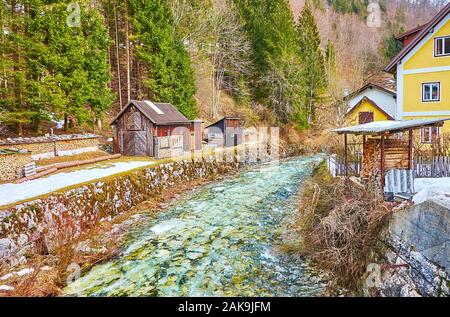 The piles of firewood and small barns stretch along the narrow canal of Traun river in Ebenzee, Salzkammergut, Austria Stock Photo