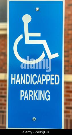 Vertical frame Close up of Handicapped Parking sign against blurred red brick wall of church Stock Photo