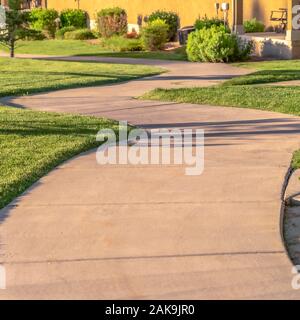 Square frame Close up of narrow paved pathway winding through lush grasses on a sunny day Stock Photo