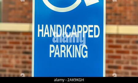 Pano Close up of Handicapped Parking sign against blurred red brick wall of church Stock Photo