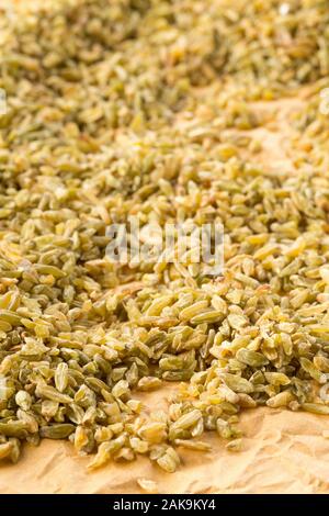 Heap of uncooked, raw freekeh or firik, roasted wheat grain, on brown packing paper background with selective focus Stock Photo