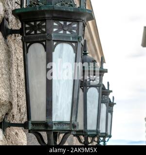 Square Close up of vintage style iron lanterns on the white stone wall of building Stock Photo