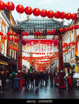 London, UK/Europe; 20/12/2019: Chinese gate and red lanterns in Chinatown in the district of Soho in London. People walking and shopping in the street Stock Photo